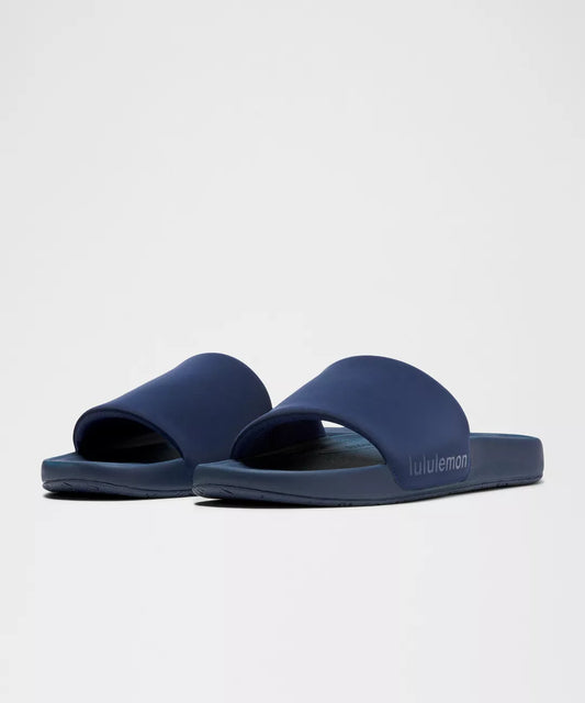 Pair of navy blue slides with 'Lululemon' branding on a light gray background