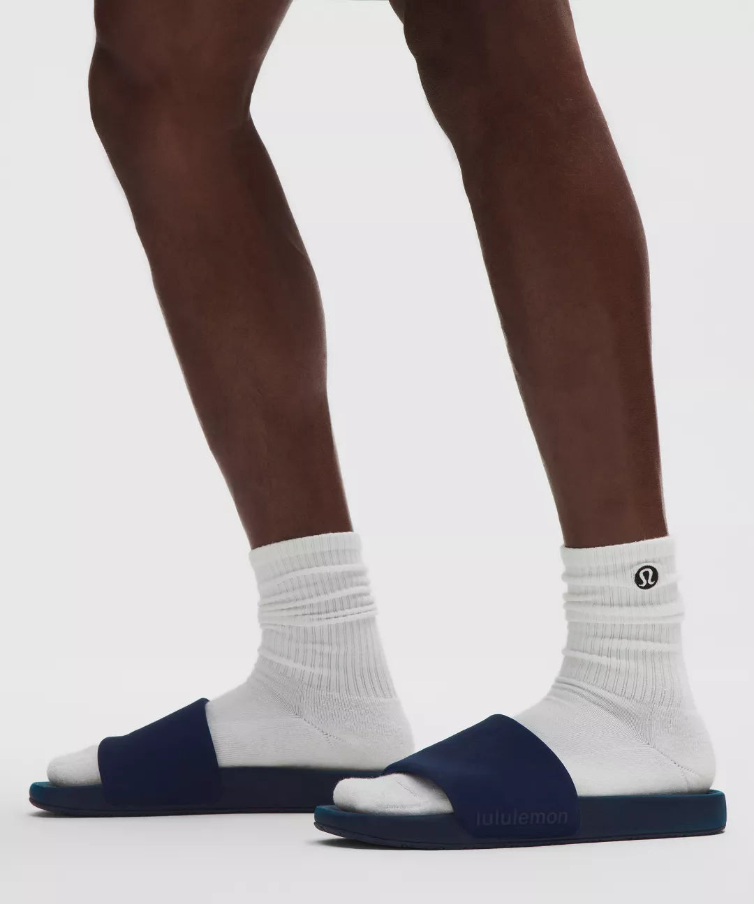 Person wearing navy sandals with white socks on a light gray background