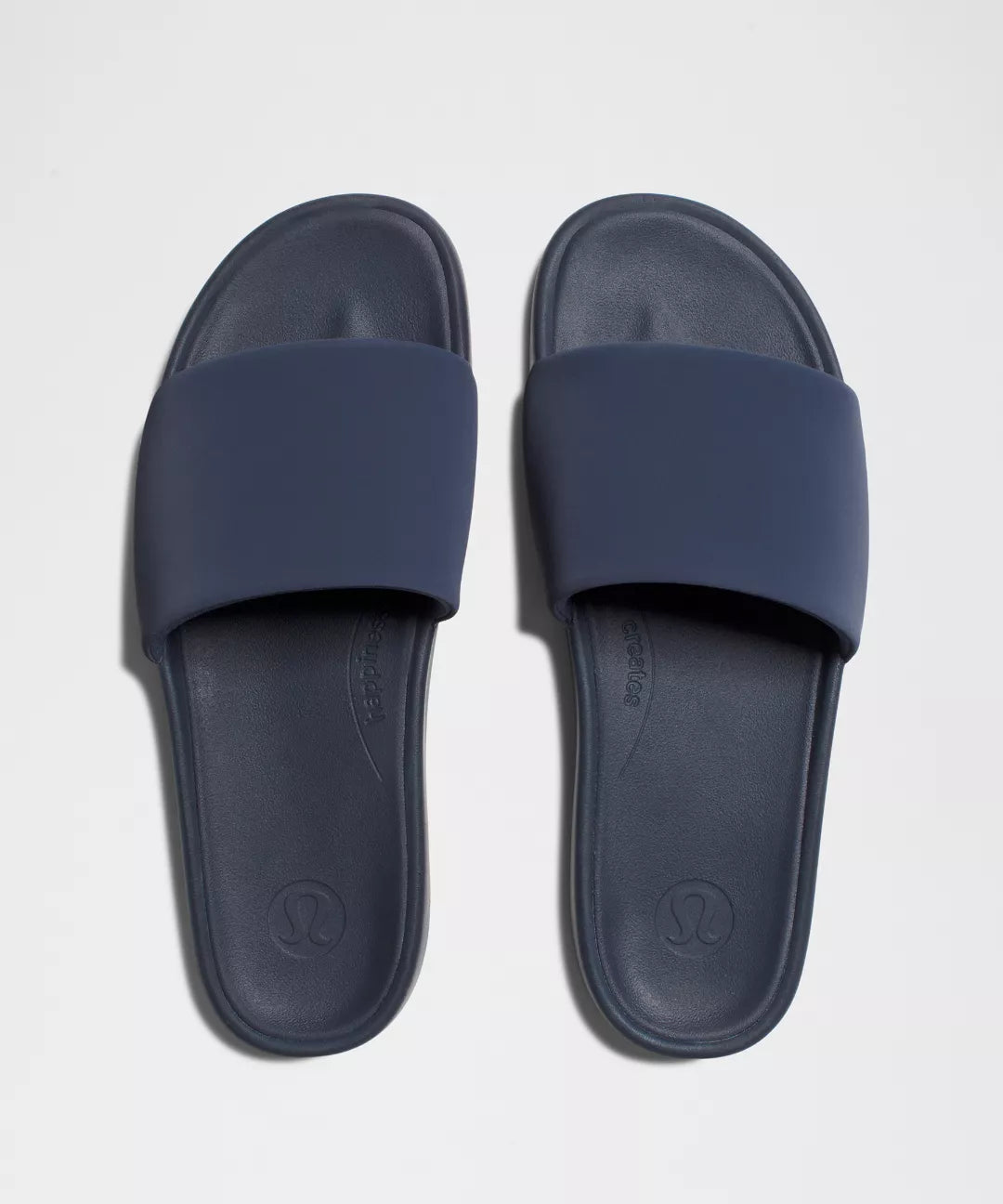 Pair of navy blue slides on a light gray background