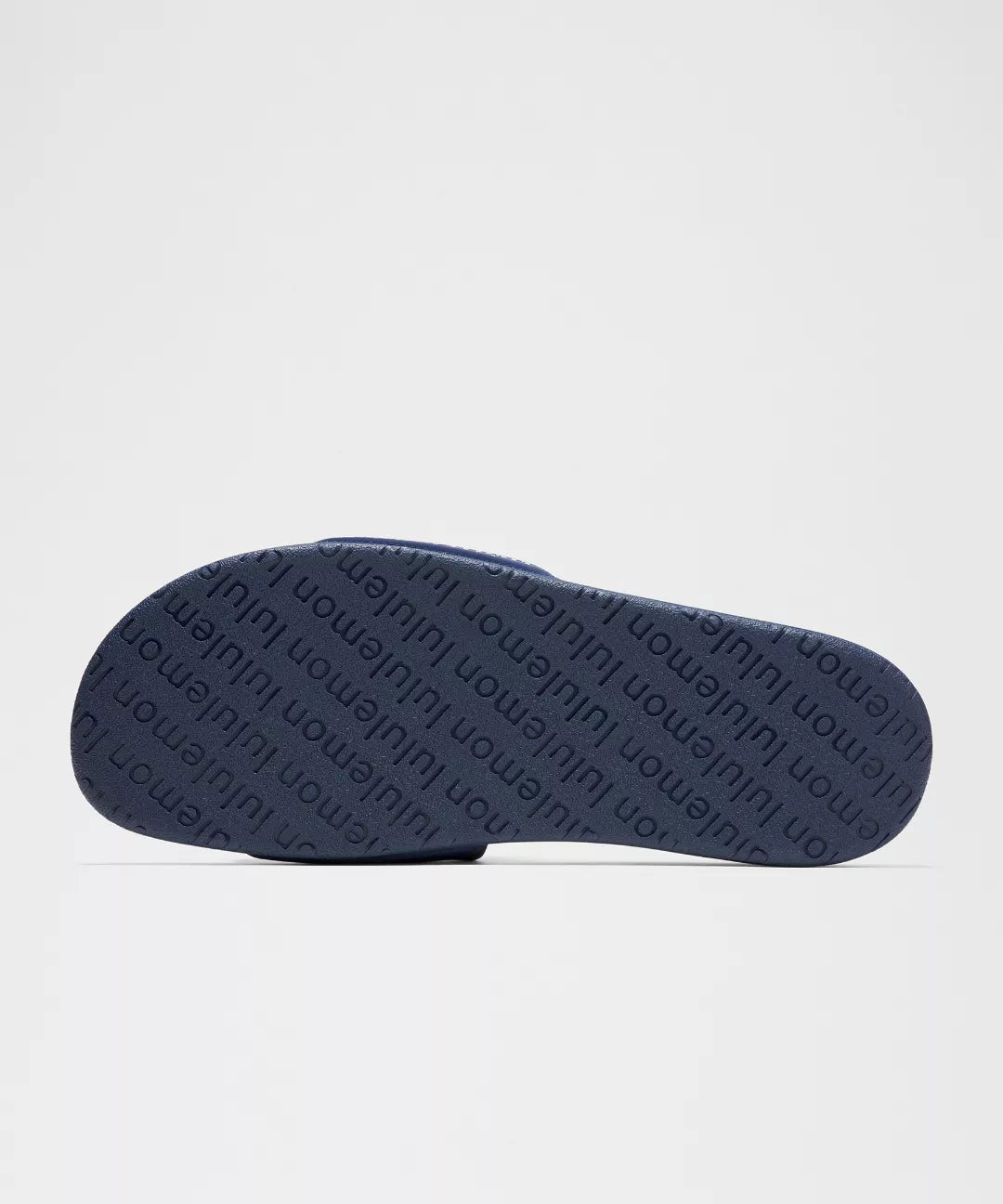 Navy blue sandal with brand name on the sole against a light gray background