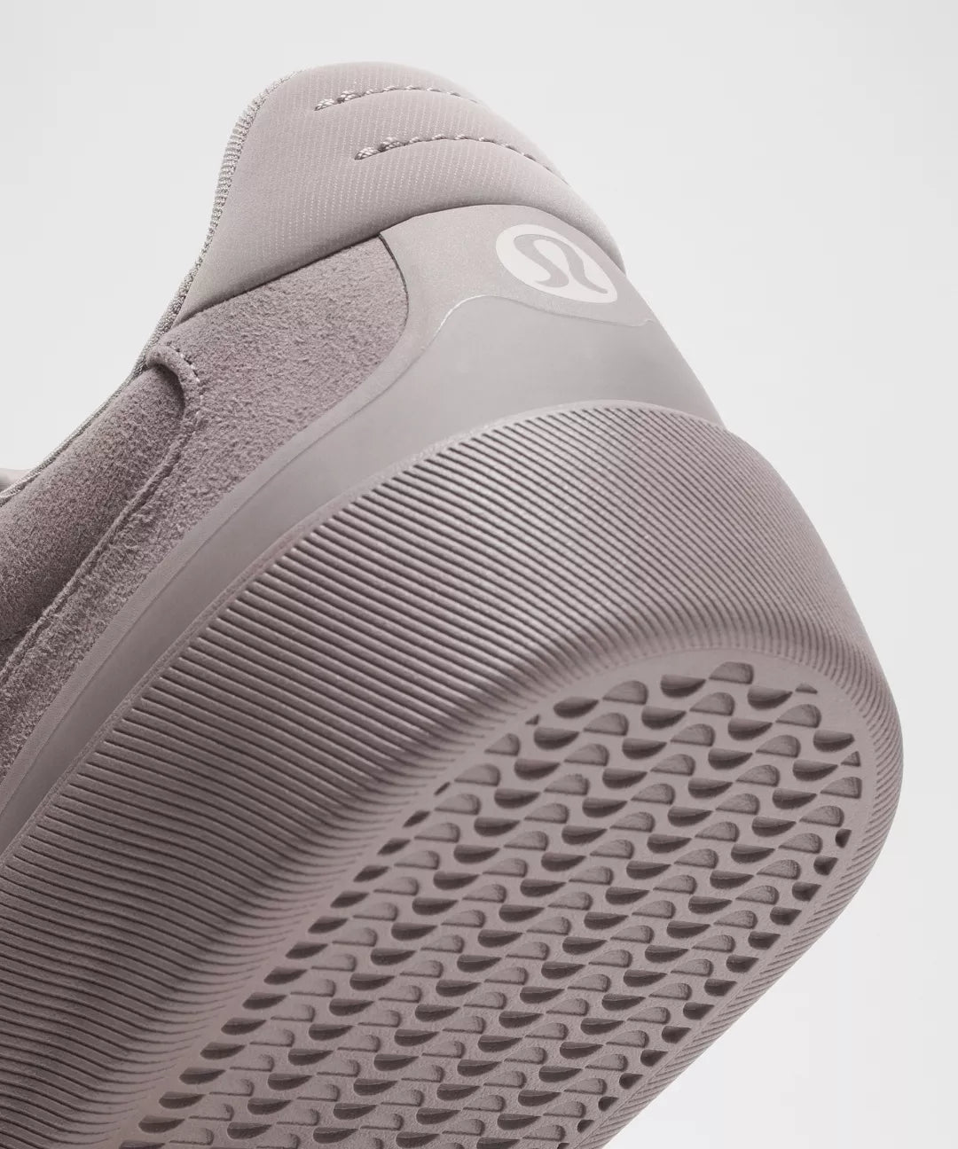 Close-up of a gray sneaker with textured sole on a light gray background