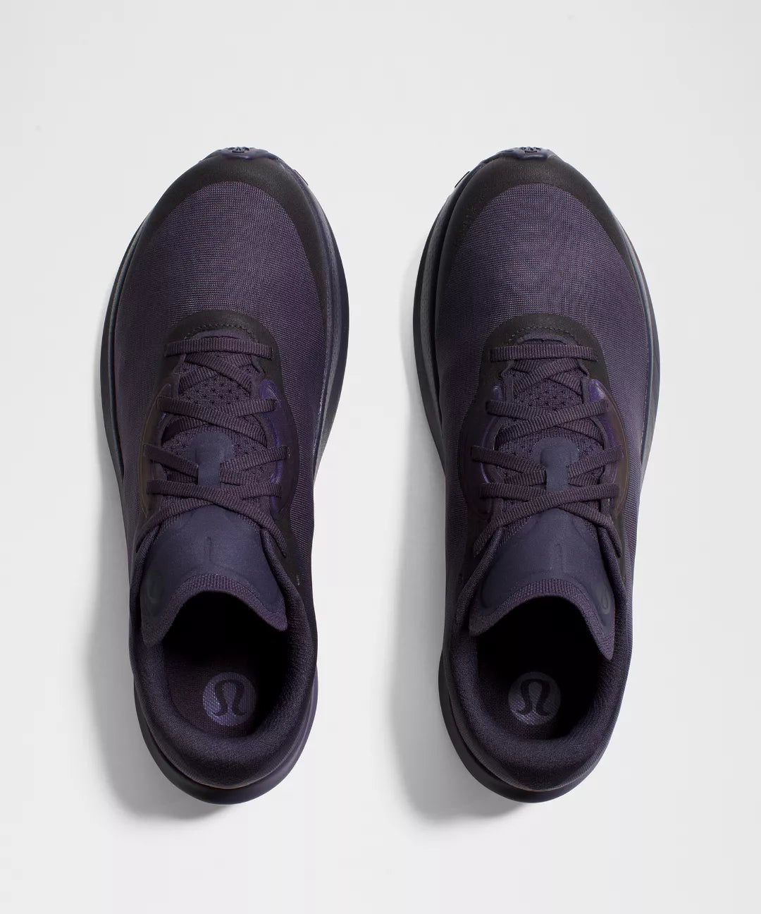 Pair of dark purple athletic shoes on a light gray background