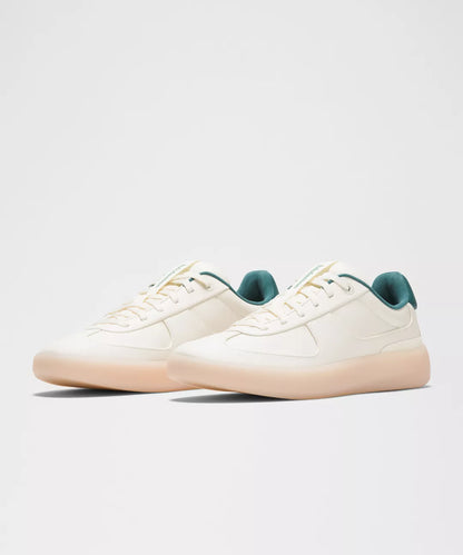 White sneakers with green accents on a light gray background