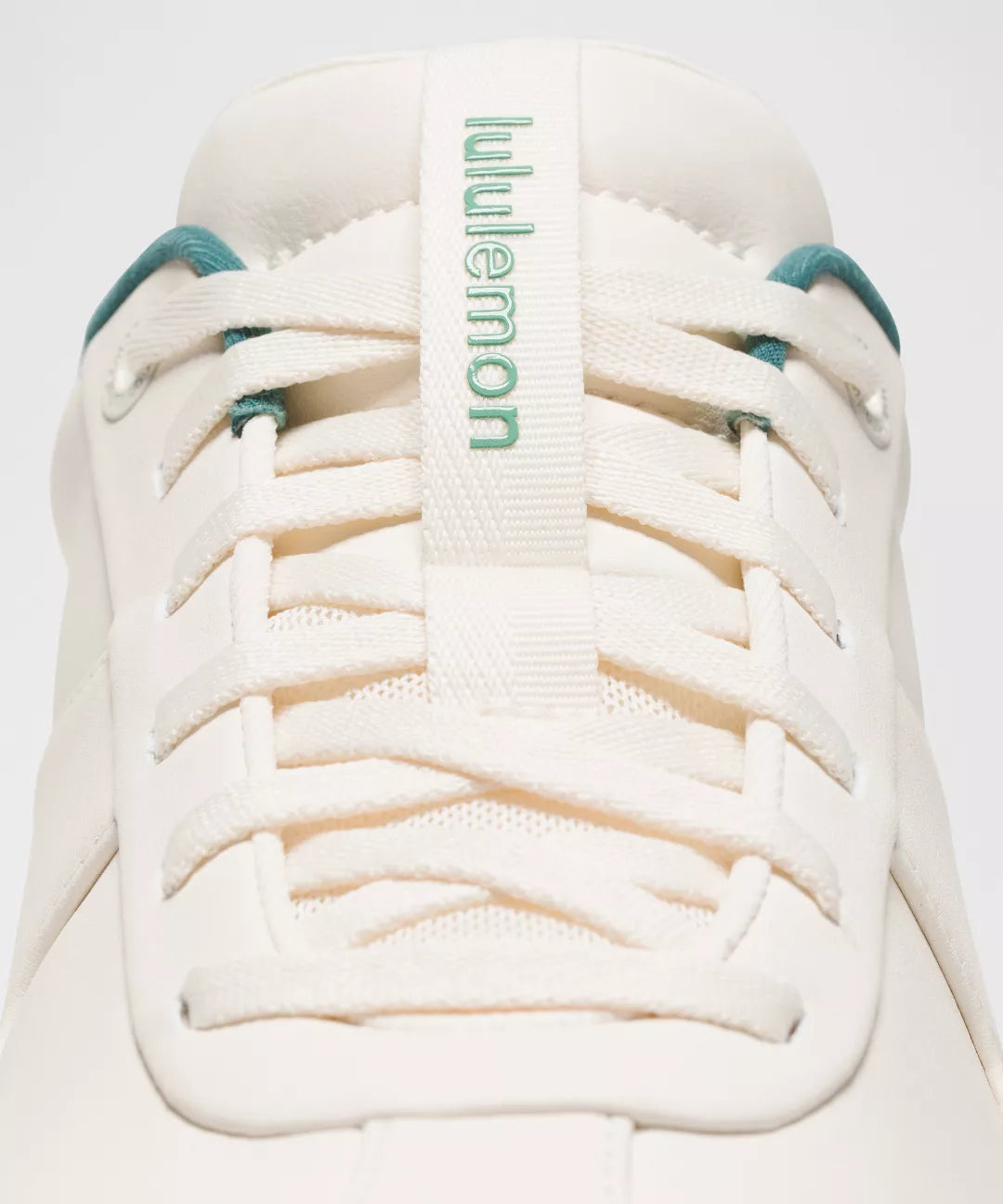 White sneaker with teal accents and 'lululemon' branding on a white background