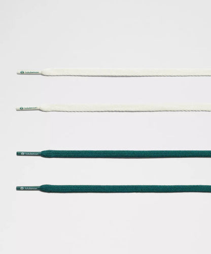 Set of white and green shoelaces on a light gray background