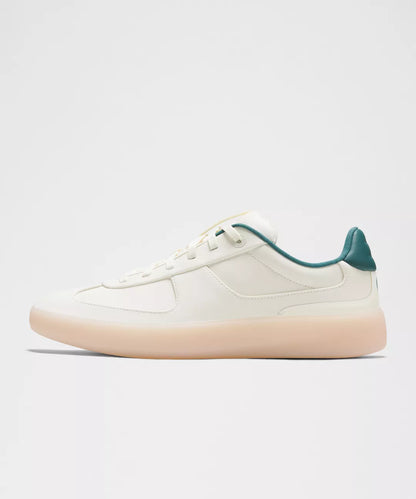 White sneaker with green accents on a light gray background