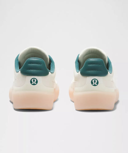White sneakers with teal accents and a visible brand logo on a light gray background