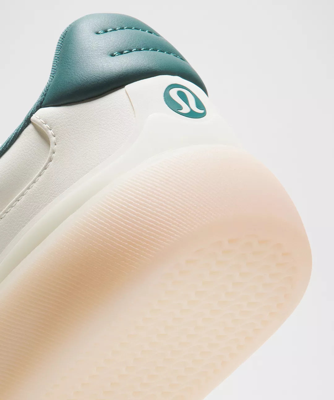 Close-up of a shoe with a green strap and visible brand logo on a light background