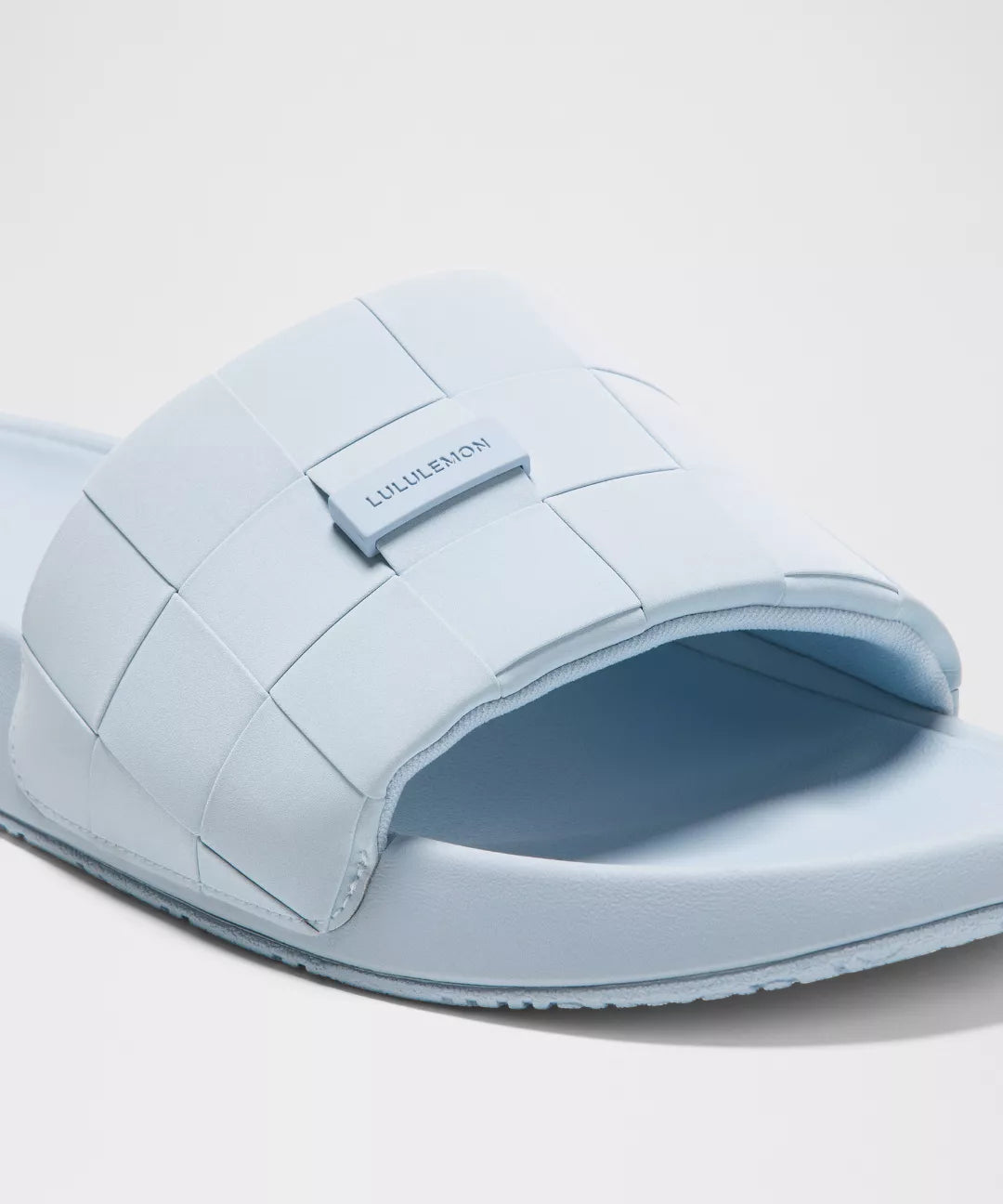 Light blue slide sandal with brand logo on a light gray background