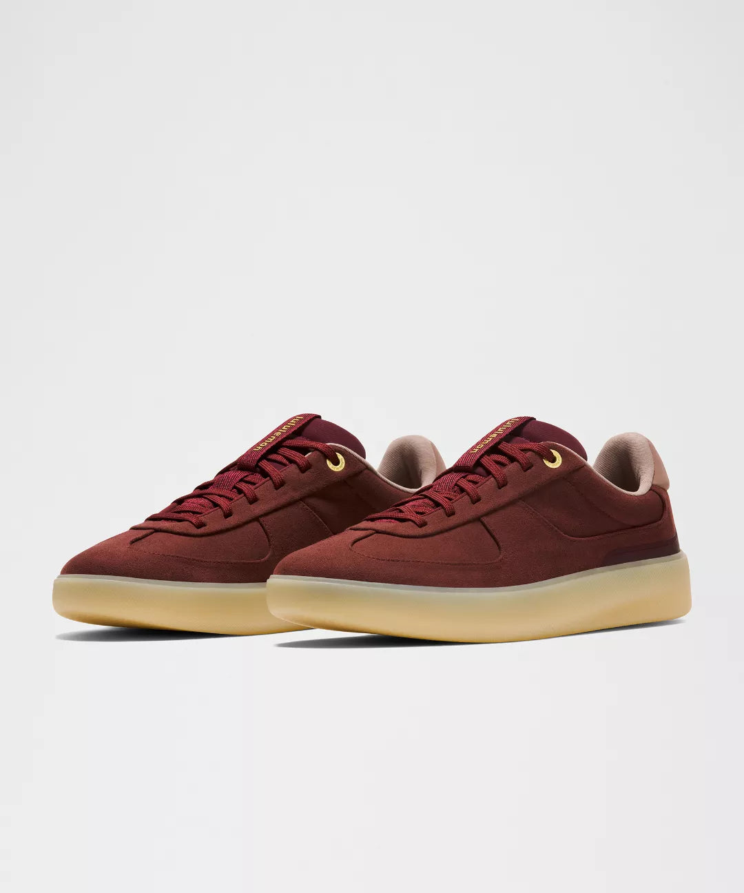 Pair of maroon sneakers with beige soles on a light gray background