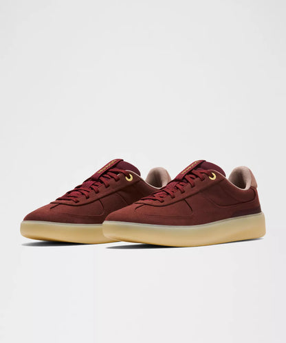 Pair of maroon sneakers with beige soles on a light gray background