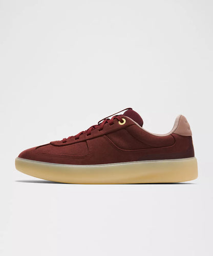 Maroon sneaker with a light brown sole on a white background
