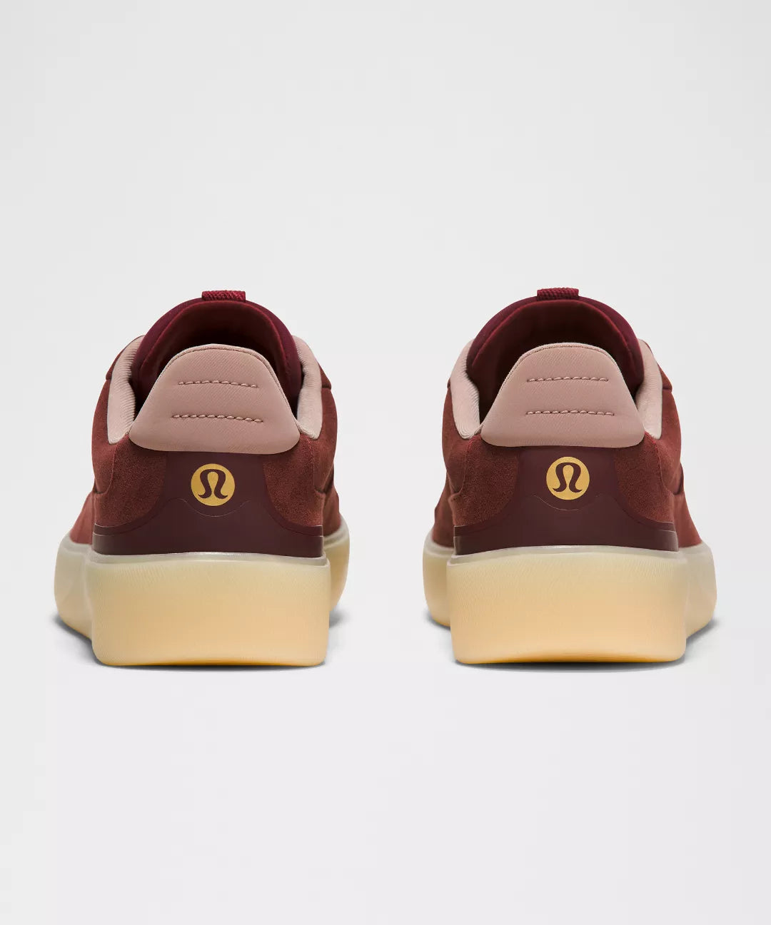 Maroon sneakers with a visible brand logo on a light gray background