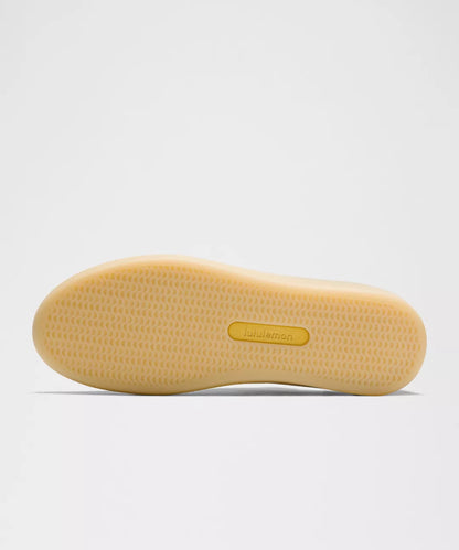 Yellow sole of a shoe with a brand label on a light gray background