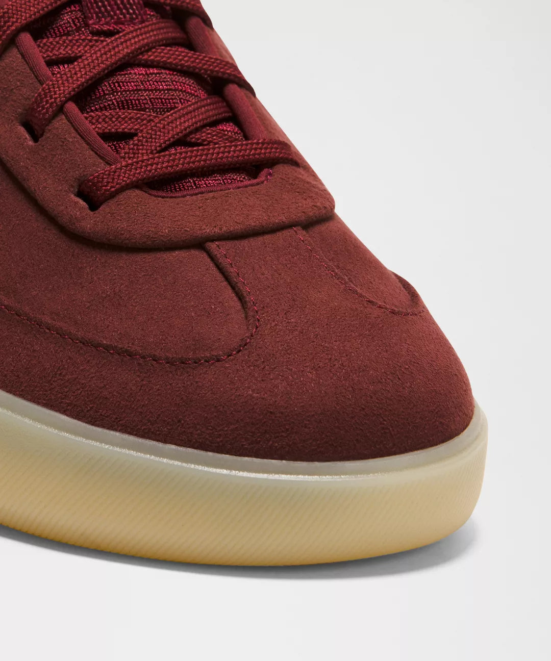 Maroon sneaker with a beige sole on a light gray background