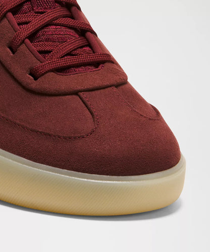 Maroon sneaker with a beige sole on a light gray background
