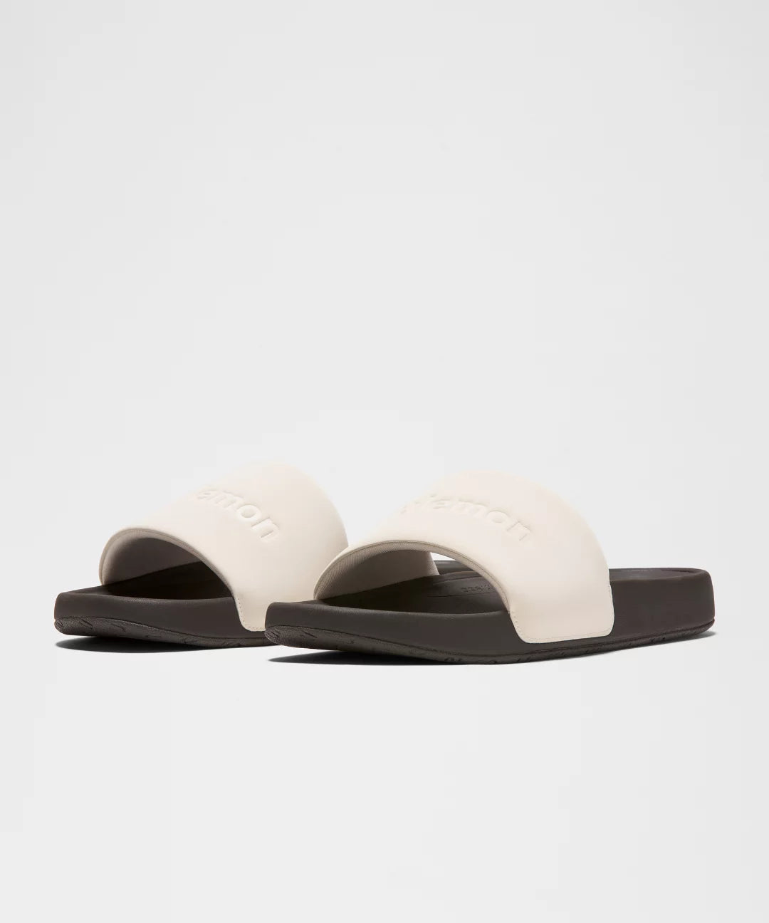 Pair of white slides with black soles on a light gray background