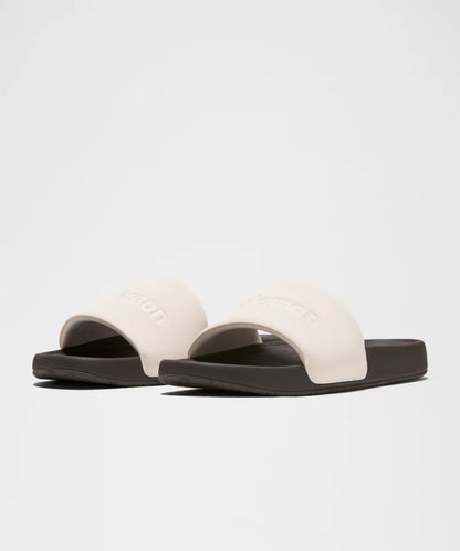 Pair of white slides with black soles on a light gray background
