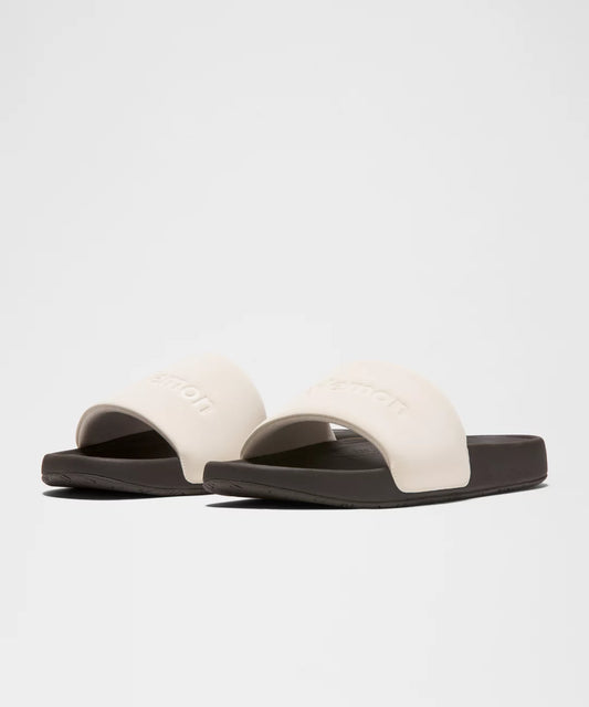 Pair of white slides with black soles on a light gray background