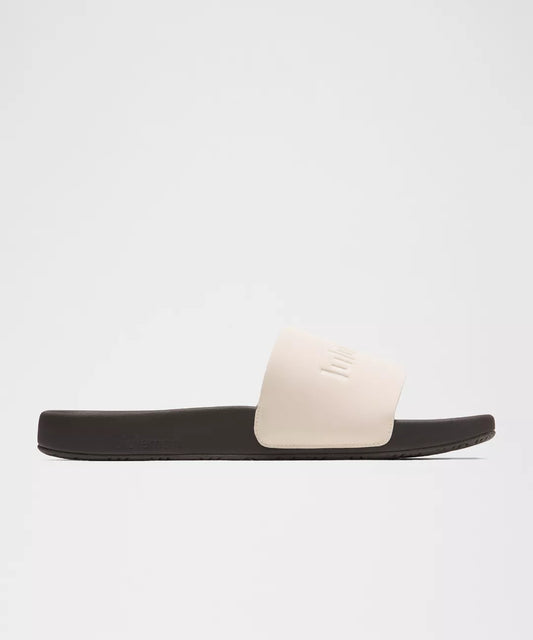 Black slide sandal with a white strap on a light gray background