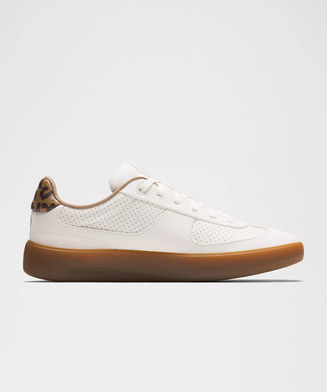 White sneaker with brown sole on a light gray background