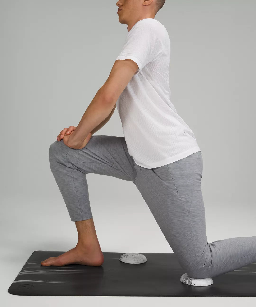 Person performing a yoga pose on a black mat with a gray background