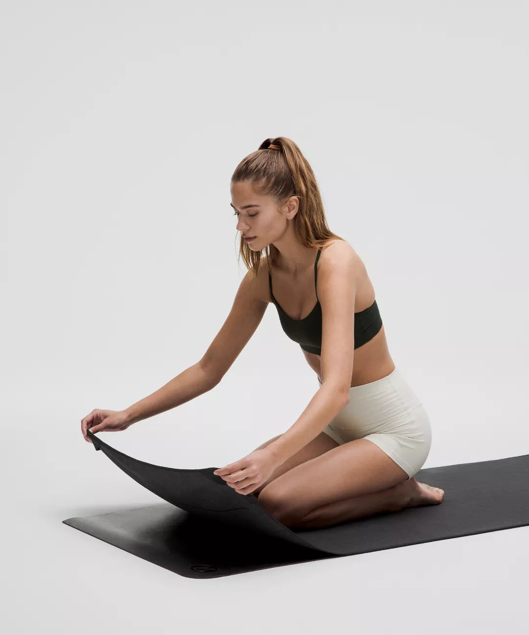Woman sitting on a yoga mat with a white background