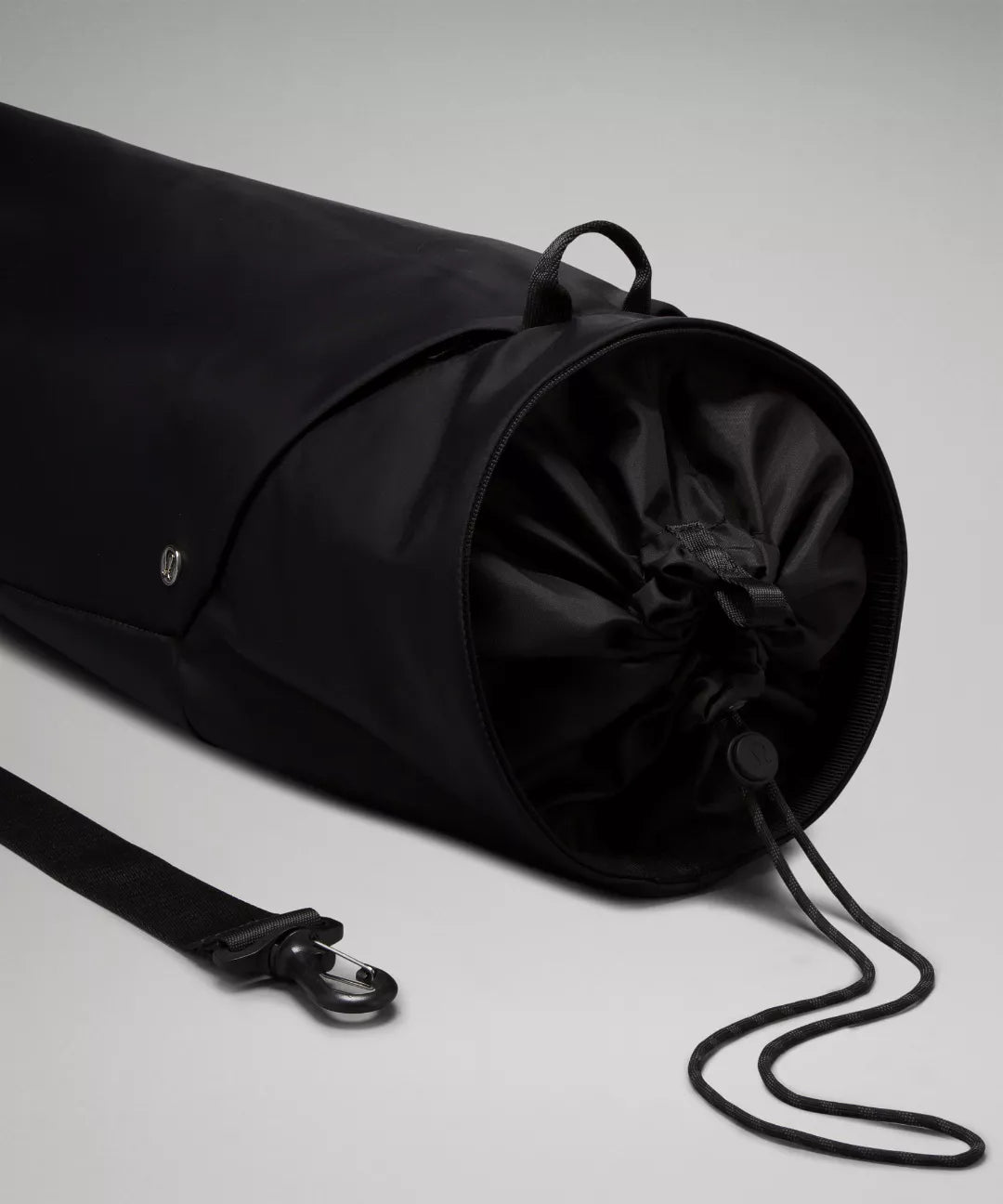 Black drawstring bag with a strap on a light gray background
