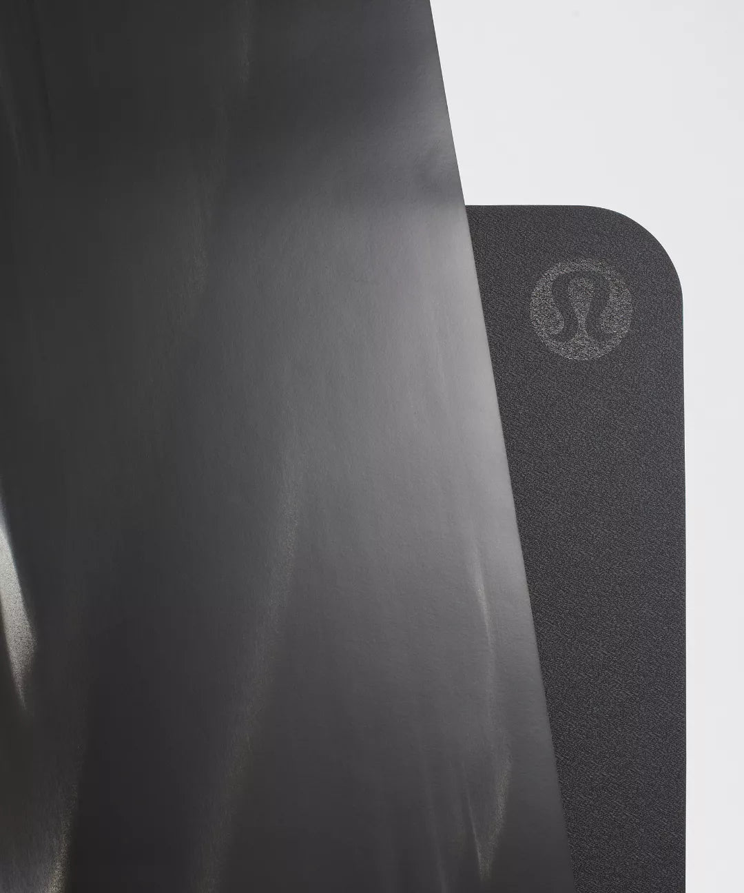 Black yoga mat with a brand logo on a light gray background