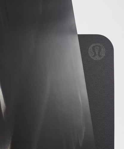 Black yoga mat with a brand logo on a light gray background