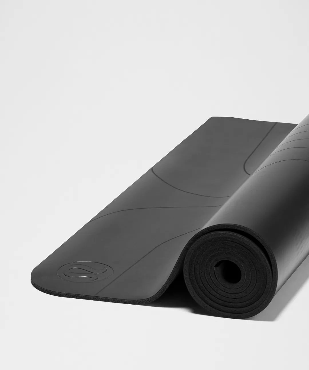 Black yoga mat with a brand logo on a light gray background