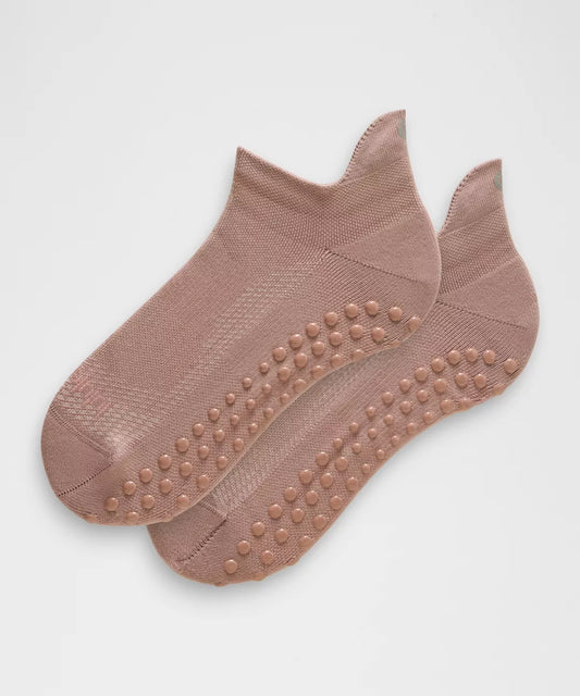 Pair of brown ankle socks with textured sole on a light gray background