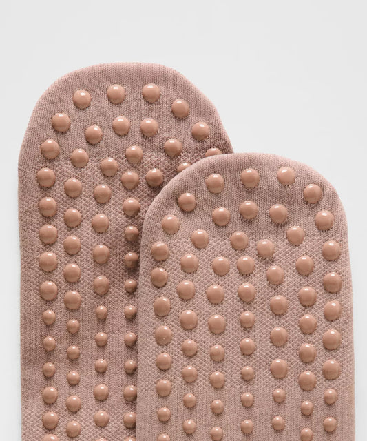 Pair of beige foot pads with textured sole on a light gray background