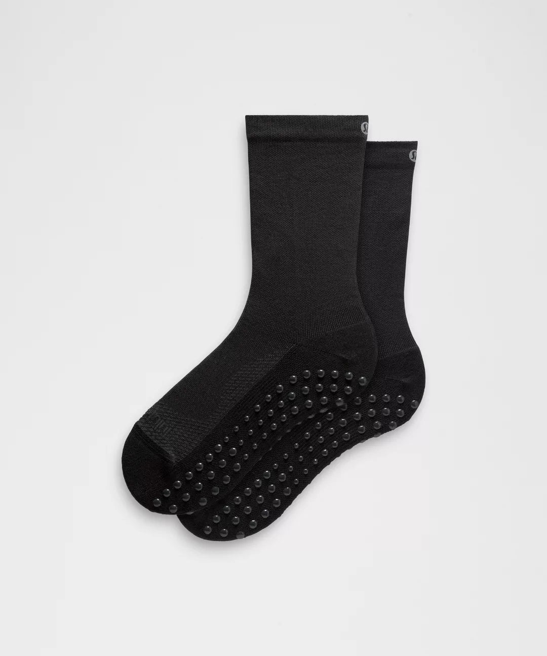 Two black socks with branding on a light gray background