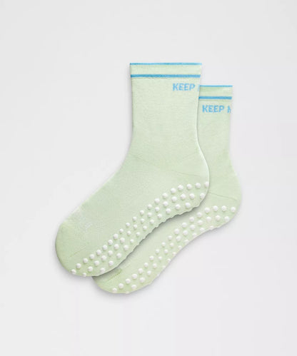 Pair of green socks with textured sole on a light gray background