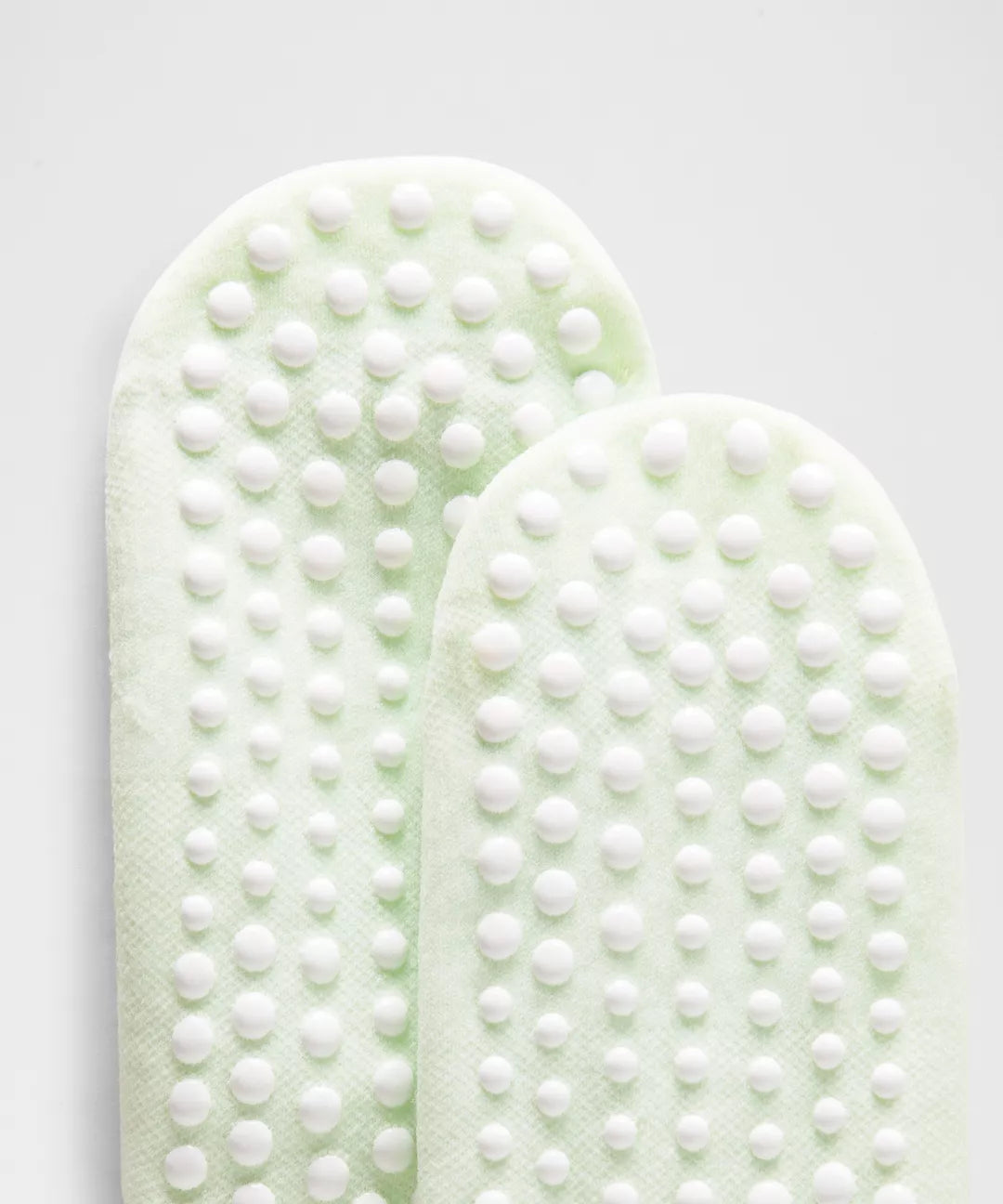 Two green foot pads with white textured surface on a light gray background