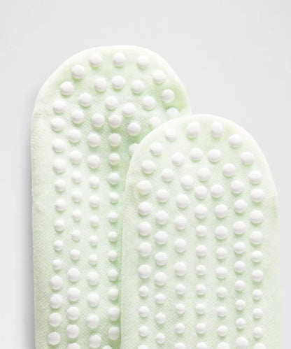 Two green foot pads with white textured surface on a light gray background