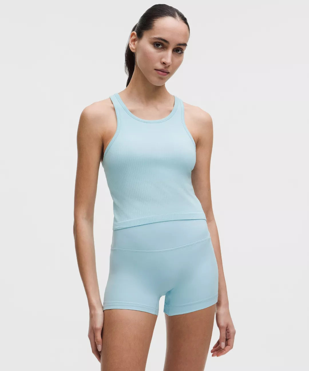 Woman wearing a light blue athletic outfit on a plain background