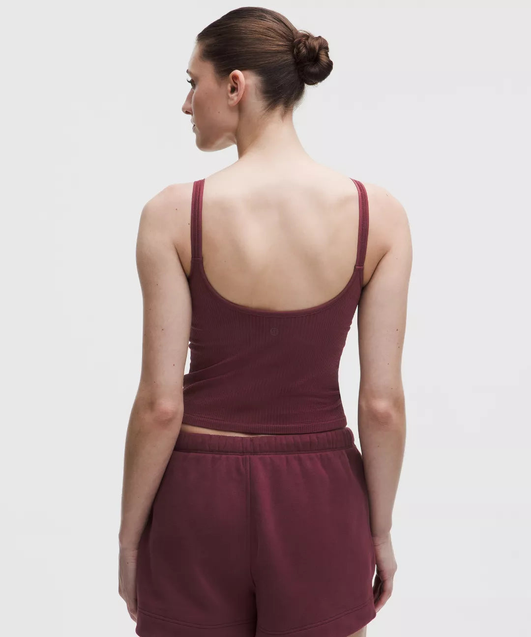 Woman wearing a maroon tank top and shorts on a white background