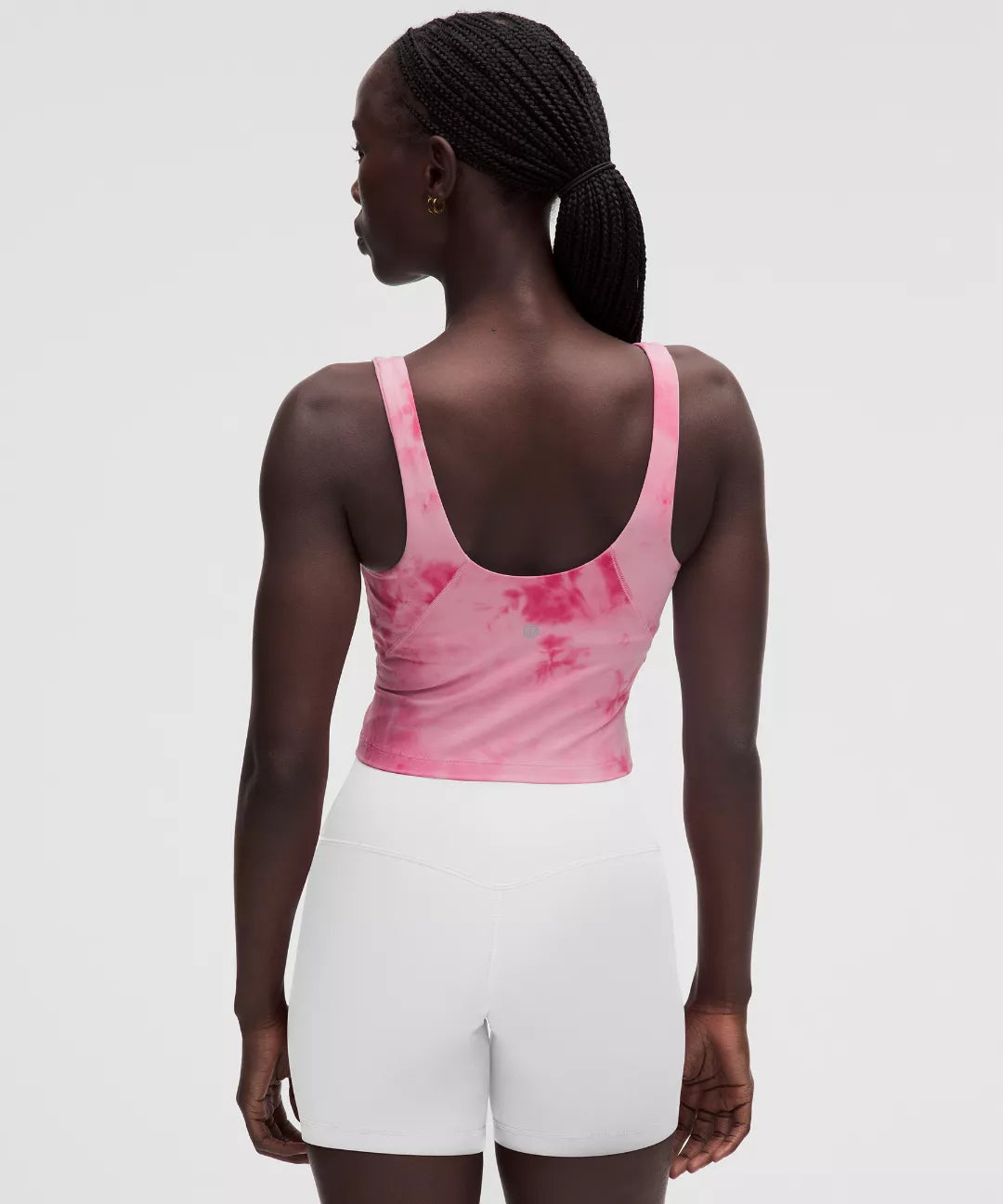 Person wearing a pink tank top and white shorts on a light gray background