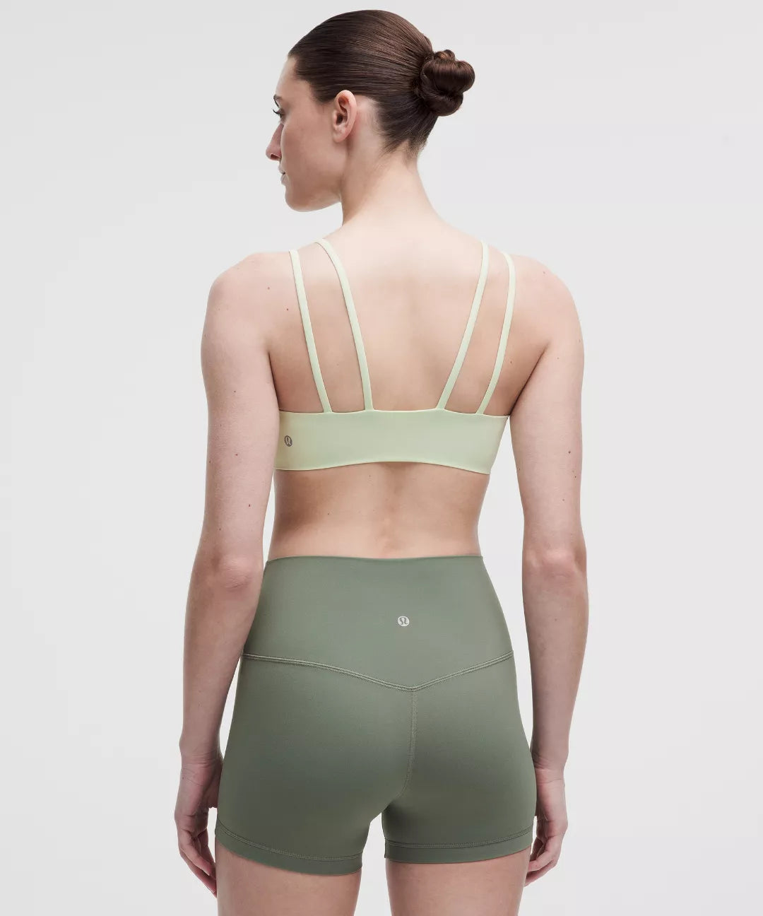 Woman wearing a green sports bra and shorts on a white background