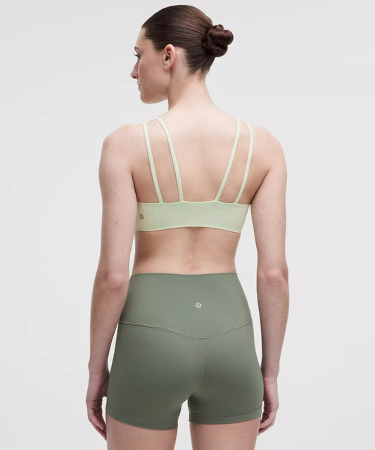 Woman wearing a green sports bra and shorts on a white background