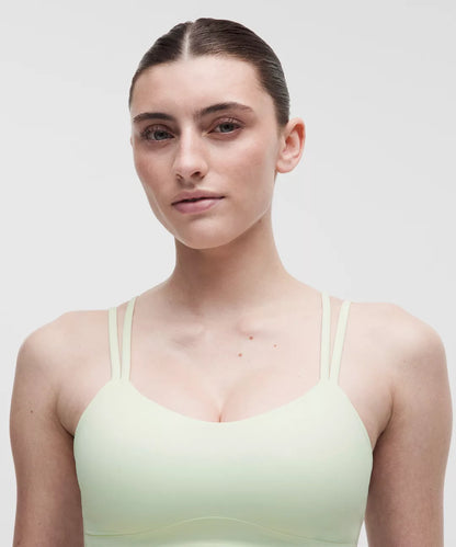 Woman wearing a light green tank top against a plain background