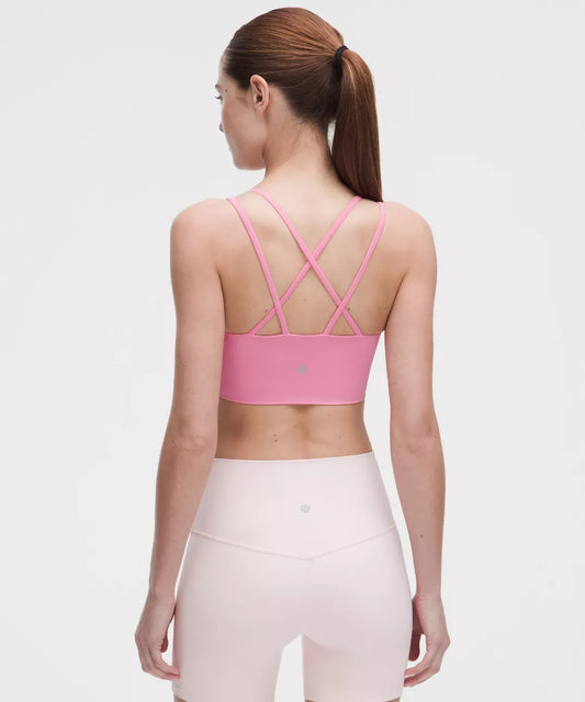 Woman wearing a pink sports bra and leggings on a white background