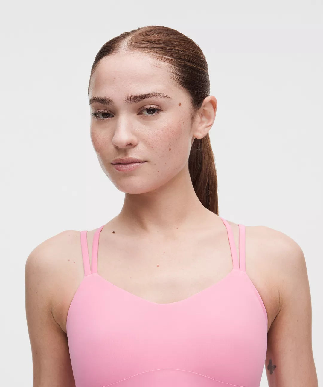 Woman wearing a pink tank top against a white background