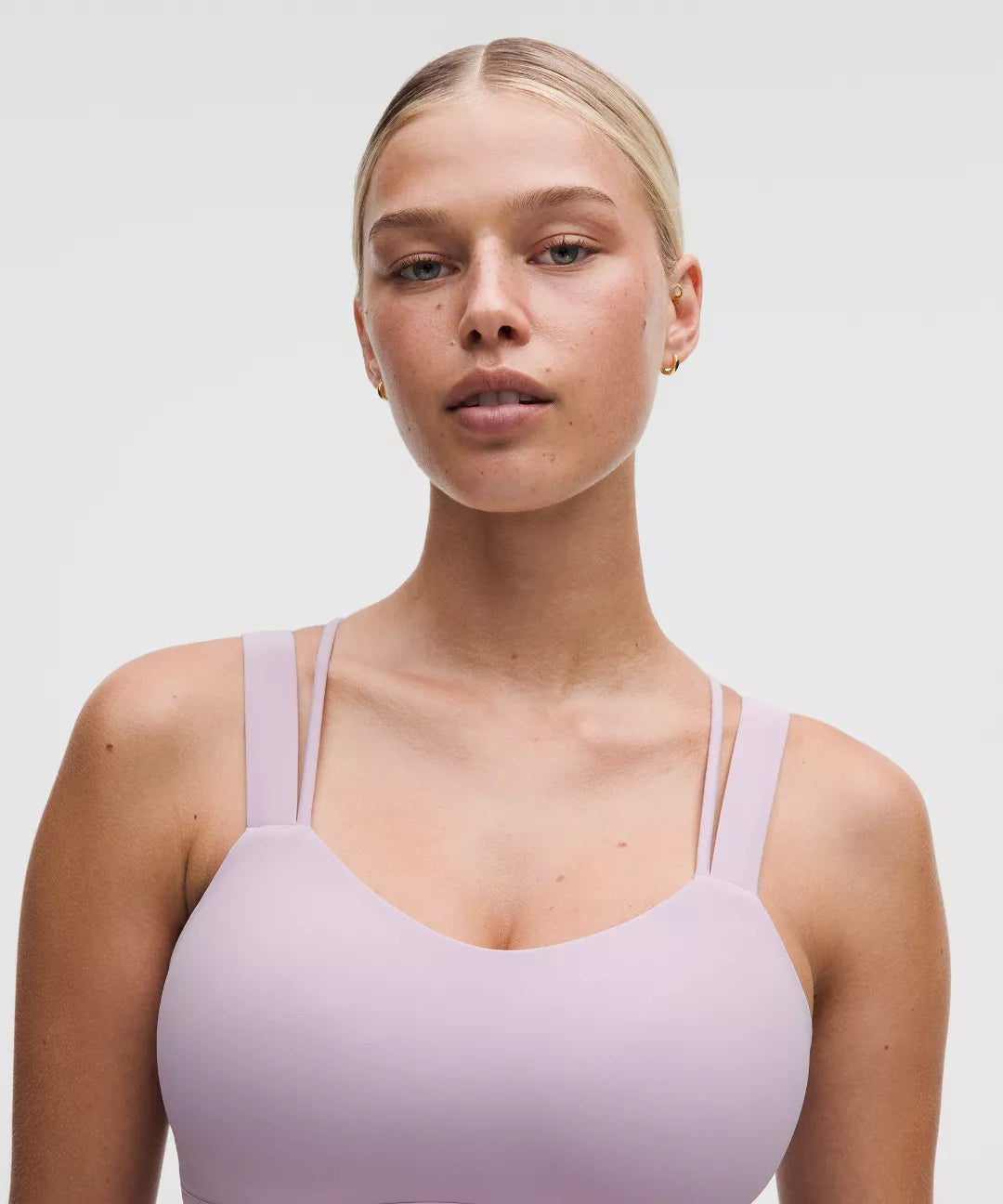 Woman wearing a light purple tank top against a plain background