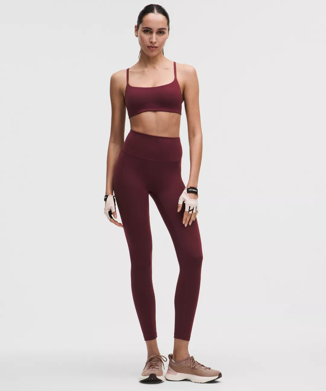 Woman wearing a maroon athletic outfit on a white background
