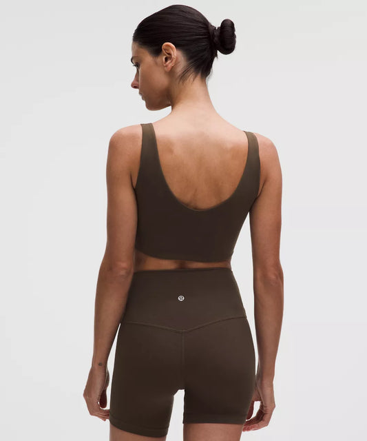 Woman wearing a brown sports bra and shorts set on a white background