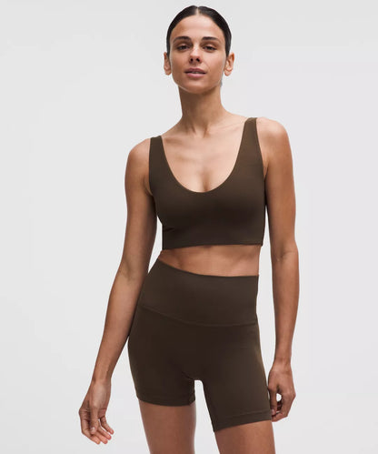Woman wearing a brown sports bra and shorts on a white background