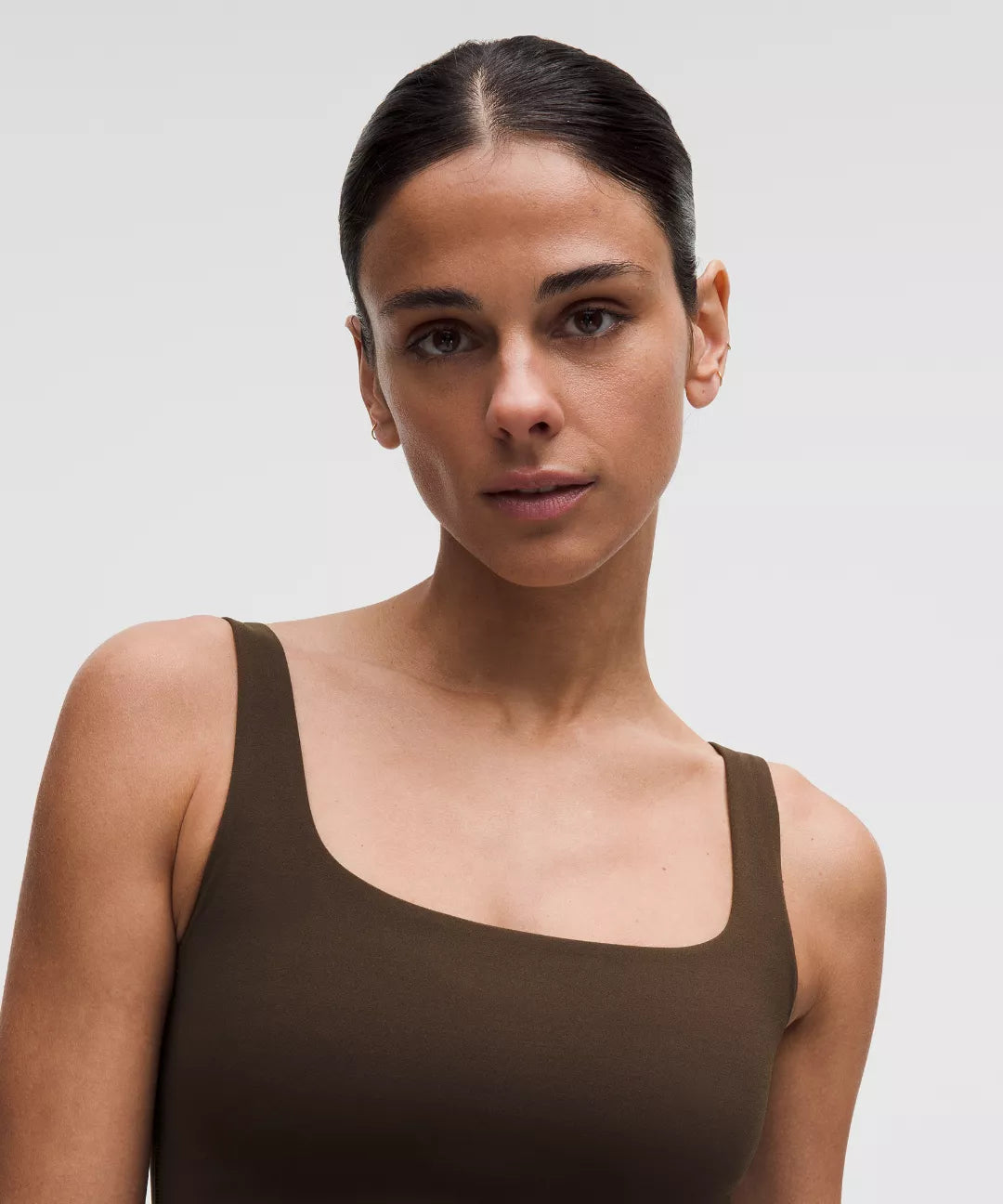 Woman wearing a brown tank top against a plain background